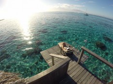 woman relaxing in a sunchair on her overwater bungalow deck in french polynesia